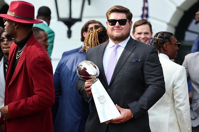 Creed in a suit and sunglasses holding a trophy