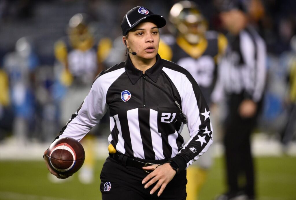 Maia chake, holding a football on the field.